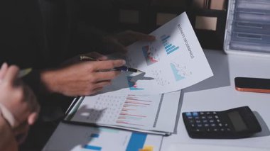 Ofiste çalışan denetçi ve muhasebeci ekibi mali verileri ve muhasebe kayıtlarını hesap makinesiyle analiz ediyor. Muhasebe şirketi kârlı nakit akışı için finansman ve vergilendirme planlaması sağlıyor