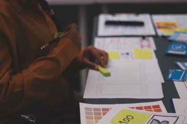 Uxui tasarımcılarından oluşan bir ekip bilgisayar ekranını işaret ederek ofiste yeni mobil uygulama tasarımını tartışıyor.