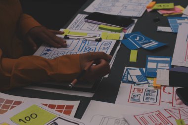 Uxui tasarımcılarından oluşan bir ekip bilgisayar ekranını işaret ederek ofiste yeni mobil uygulama tasarımını tartışıyor.