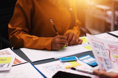 Uxui tasarımcılarından oluşan bir ekip bilgisayar ekranını işaret ederek ofiste yeni mobil uygulama tasarımını tartışıyor.