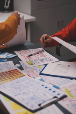 Uxui tasarımcılarından oluşan bir ekip bilgisayar ekranını işaret ederek ofiste yeni mobil uygulama tasarımını tartışıyor.