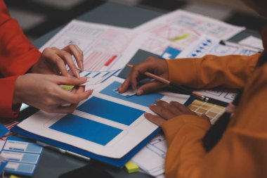 Uxui tasarımcılarından oluşan bir ekip bilgisayar ekranını işaret ederek ofiste yeni mobil uygulama tasarımını tartışıyor.