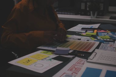 Uxui tasarımcılarından oluşan bir ekip bilgisayar ekranını işaret ederek ofiste yeni mobil uygulama tasarımını tartışıyor.