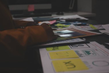 Uxui tasarımcılarından oluşan bir ekip bilgisayar ekranını işaret ederek ofiste yeni mobil uygulama tasarımını tartışıyor.