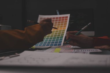 Uxui tasarımcılarından oluşan bir ekip bilgisayar ekranını işaret ederek ofiste yeni mobil uygulama tasarımını tartışıyor.