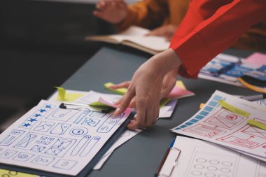 Uxui tasarımcılarından oluşan bir ekip bilgisayar ekranını işaret ederek ofiste yeni mobil uygulama tasarımını tartışıyor.