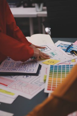 Uxui tasarımcılarından oluşan bir ekip bilgisayar ekranını işaret ederek ofiste yeni mobil uygulama tasarımını tartışıyor.