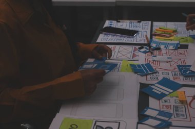 Uxui tasarımcılarından oluşan bir ekip bilgisayar ekranını işaret ederek ofiste yeni mobil uygulama tasarımını tartışıyor.