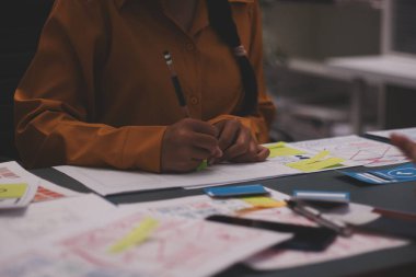 Uxui tasarımcılarından oluşan bir ekip bilgisayar ekranını işaret ederek ofiste yeni mobil uygulama tasarımını tartışıyor.