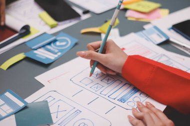 Uxui tasarımcılarından oluşan bir ekip bilgisayar ekranını işaret ederek ofiste yeni mobil uygulama tasarımını tartışıyor.