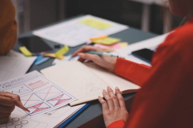 Uxui tasarımcılarından oluşan bir ekip bilgisayar ekranını işaret ederek ofiste yeni mobil uygulama tasarımını tartışıyor.