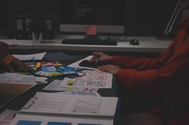 Uxui tasarımcılarından oluşan bir ekip bilgisayar ekranını işaret ederek ofiste yeni mobil uygulama tasarımını tartışıyor.