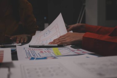 Uxui tasarımcılarından oluşan bir ekip bilgisayar ekranını işaret ederek ofiste yeni mobil uygulama tasarımını tartışıyor.