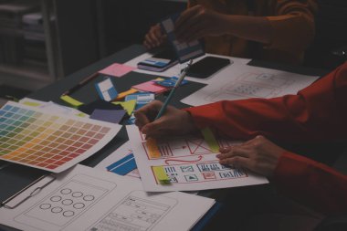 Uxui tasarımcılarından oluşan bir ekip bilgisayar ekranını işaret ederek ofiste yeni mobil uygulama tasarımını tartışıyor.