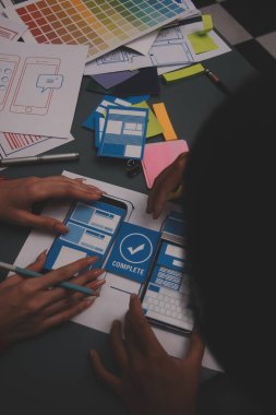 Uxui tasarımcılarından oluşan bir ekip bilgisayar ekranını işaret ederek ofiste yeni mobil uygulama tasarımını tartışıyor.