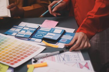 Uxui tasarımcılarından oluşan bir ekip bilgisayar ekranını işaret ederek ofiste yeni mobil uygulama tasarımını tartışıyor.