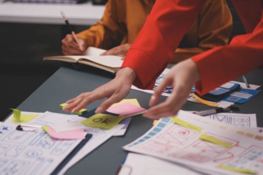 Uxui tasarımcılarından oluşan bir ekip bilgisayar ekranını işaret ederek ofiste yeni mobil uygulama tasarımını tartışıyor.