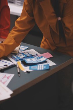 Uxui tasarımcılarından oluşan bir ekip bilgisayar ekranını işaret ederek ofiste yeni mobil uygulama tasarımını tartışıyor.