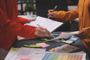 Uxui tasarımcılarından oluşan bir ekip bilgisayar ekranını işaret ederek ofiste yeni mobil uygulama tasarımını tartışıyor.