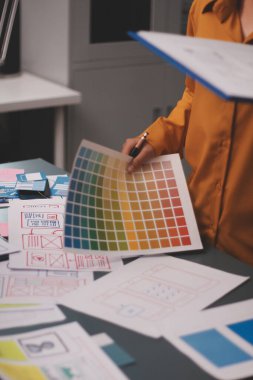 Uxui tasarımcılarından oluşan bir ekip bilgisayar ekranını işaret ederek ofiste yeni mobil uygulama tasarımını tartışıyor.