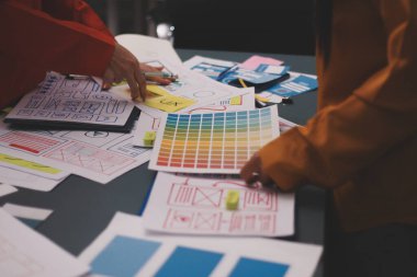 Uxui tasarımcılarından oluşan bir ekip bilgisayar ekranını işaret ederek ofiste yeni mobil uygulama tasarımını tartışıyor.