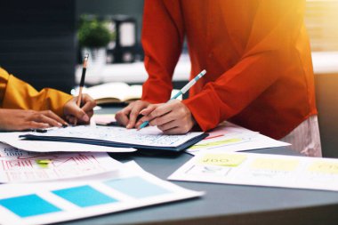 Uxui tasarımcılarından oluşan bir ekip bilgisayar ekranını işaret ederek ofiste yeni mobil uygulama tasarımını tartışıyor.