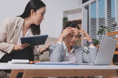 İki iş kadını ofiste dizüstü bilgisayarla çalışırken stresli hissediyorlar