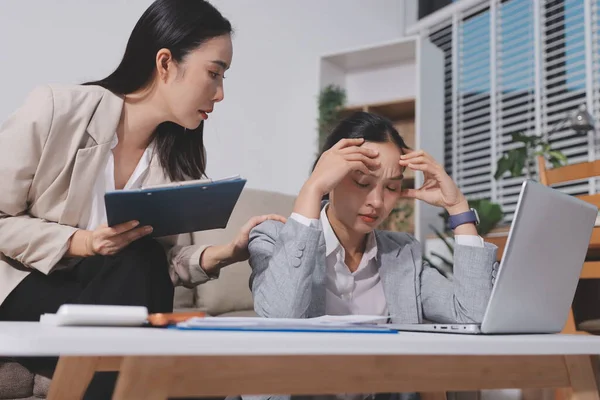 İki iş kadını ofiste dizüstü bilgisayarla çalışırken stresli hissediyorlar