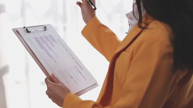 Yakınlarda grafikleri ve dizüstü bilgisayarı olan bir hesap makinesinde finansal veri hesaplayan bir kişi