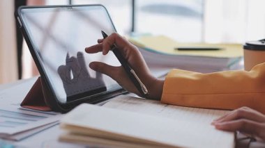 Yakınlarda grafikleri ve dizüstü bilgisayarı olan bir hesap makinesinde finansal veri hesaplayan bir kişi