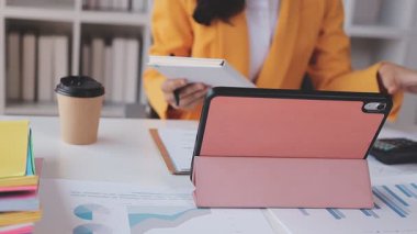 Yakınlarda grafikleri ve dizüstü bilgisayarı olan bir hesap makinesinde finansal veri hesaplayan bir kişi