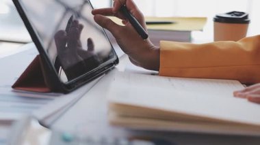 Yakınlarda grafikleri ve dizüstü bilgisayarı olan bir hesap makinesinde finansal veri hesaplayan bir kişi