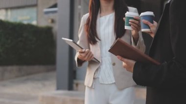 İş adamları modern ofisin önünde yürür ve birbirleriyle konuşurlar.