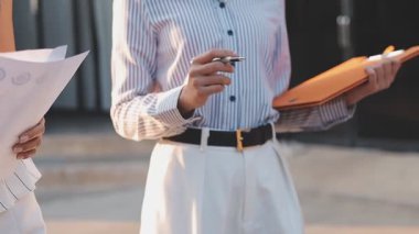 İş adamları modern ofisin önünde yürür ve birbirleriyle konuşurlar.