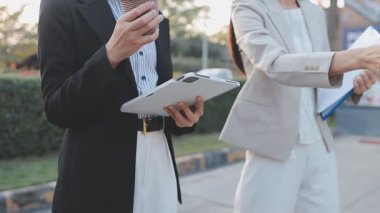 İş adamları modern ofisin önünde yürür ve birbirleriyle konuşurlar.