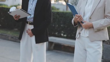 İş adamları modern ofisin önünde yürür ve birbirleriyle konuşurlar.