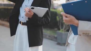 İş adamları modern ofisin önünde yürür ve birbirleriyle konuşurlar.