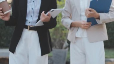 İş adamları modern ofisin önünde yürür ve birbirleriyle konuşurlar.