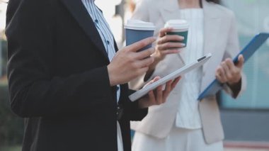 İş adamları modern ofisin önünde yürür ve birbirleriyle konuşurlar.