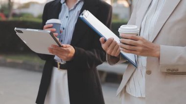 İş adamları modern ofisin önünde yürür ve birbirleriyle konuşurlar.