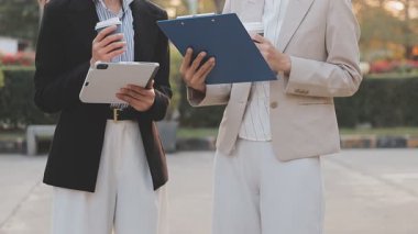 İş adamları modern ofisin önünde yürür ve birbirleriyle konuşurlar.