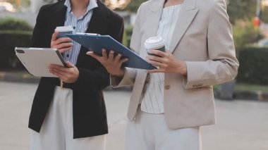 İş adamları modern ofisin önünde yürür ve birbirleriyle konuşurlar.