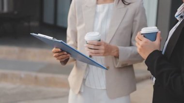 İş adamları modern ofisin önünde yürür ve birbirleriyle konuşurlar.