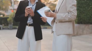 İş adamları modern ofisin önünde yürür ve birbirleriyle konuşurlar.