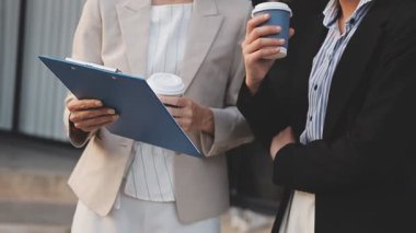 İş adamları modern ofisin önünde yürür ve birbirleriyle konuşurlar.