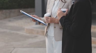 İş adamları modern ofisin önünde yürür ve birbirleriyle konuşurlar.