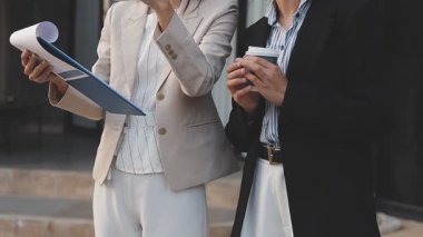 İş adamları modern ofisin önünde yürür ve birbirleriyle konuşurlar.