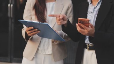 İş adamları modern ofisin önünde yürür ve birbirleriyle konuşurlar.