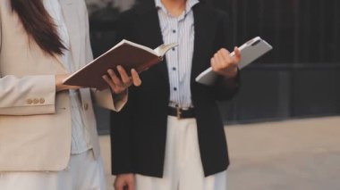 İş adamları modern ofisin önünde yürür ve birbirleriyle konuşurlar.