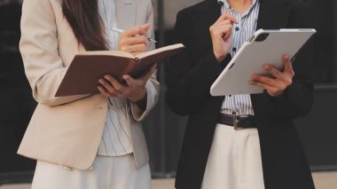 İş adamları modern ofisin önünde yürür ve birbirleriyle konuşurlar.